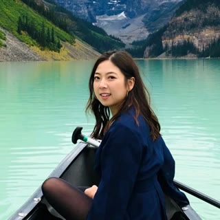 Agnes smiling over her shoulder from a canoe on a turquoise mountain lake